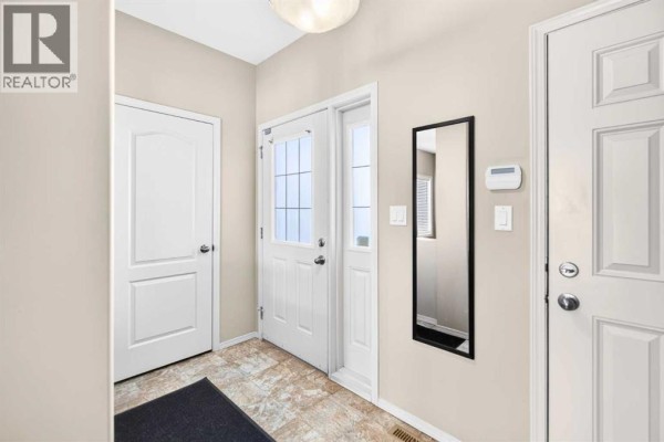 Entranceway inside the duplex with beige walls, tiled floor, and multiple doors. - 21 Pinetree Close, Blackfalds