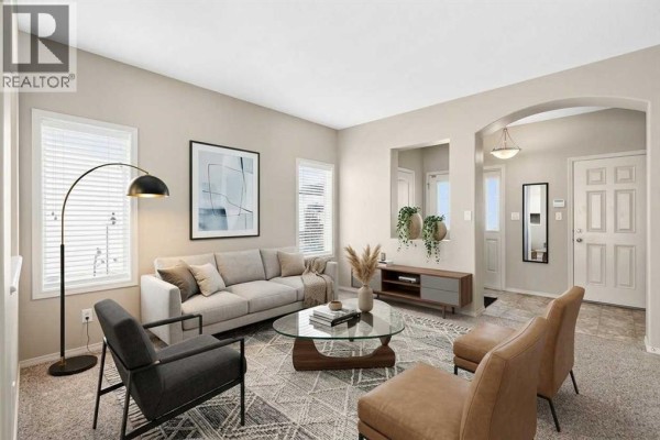Living room with a grey sofa, armchairs, glass coffee table, and large windows. - 21 Pinetree Close, Blackfalds
