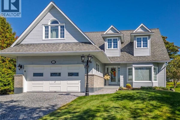 Front exterior of a two-story residential house with grey vinyl siding and a paved driveway. - 21 Principale Street, Riviere Verte