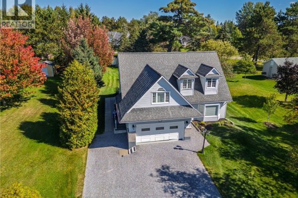 High-angle view of a grey house with a manicured lawn and surrounding trees in autumn colors. - 21 Principale Street, Riviere Verte