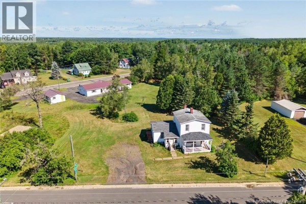 Wider aerial view of the property showing the house, surrounding trees, and neighboring buildings. - 21 Red Bank Drive, Chipman