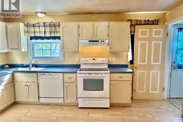Kitchen with a white stove, dishwasher, sink, and light wood cabinets. - 21 Second Street, Miramichi