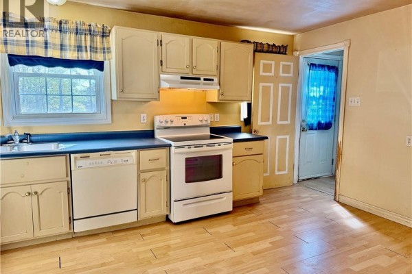 Kitchen with light wood floor, white appliances, and a blue countertop. - 21 Second Street, Miramichi