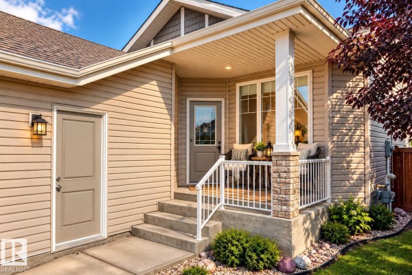 Close-up of the house entrance with beige siding, a covered porch, and steps. - 21 Silverstone Dr Nw, Stony Plain
