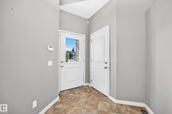 Interior entryway with beige tiled floor, grey walls, and two white doors. - 21 Silverstone Dr Nw, Stony Plain