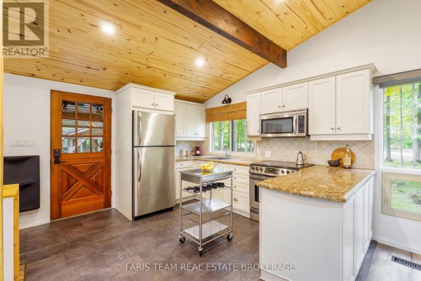 Kitchen with white cabinets, stainless steel appliances, granite countertops, and wood ceiling. - 21 Slalom Drive, Oro Medonte