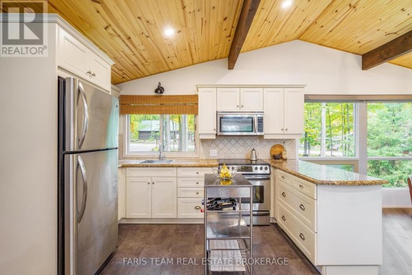 Kitchen with white cabinetry, stainless appliances, granite countertops, and vaulted wood ceiling. - 21 Slalom Drive, Oro Medonte
