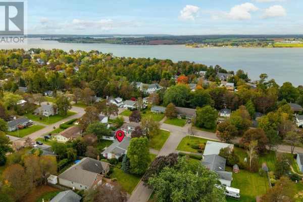 Aerial view of a residential neighborhood with houses, trees, and a body of water in the distance. - 21 Smallwood Crescent, Charlottetown