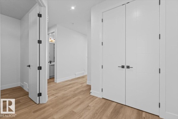 Hallway with white walls, light wood flooring, and a large double closet with modern handles. - 21 Sorel Av, Beaumont