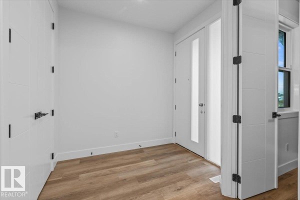 Interior hallway with white walls, light wood floors, and a decorative dark grey paneled wall. - 21 Sorel Av, Beaumont