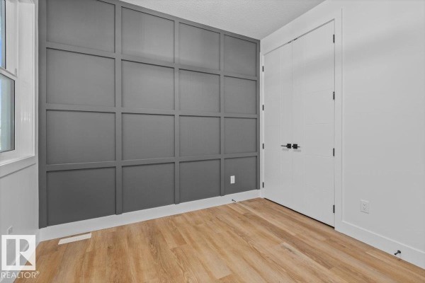Room with white walls, light wood flooring, and a large dark grey geometric paneled feature wall. - 21 Sorel Av, Beaumont