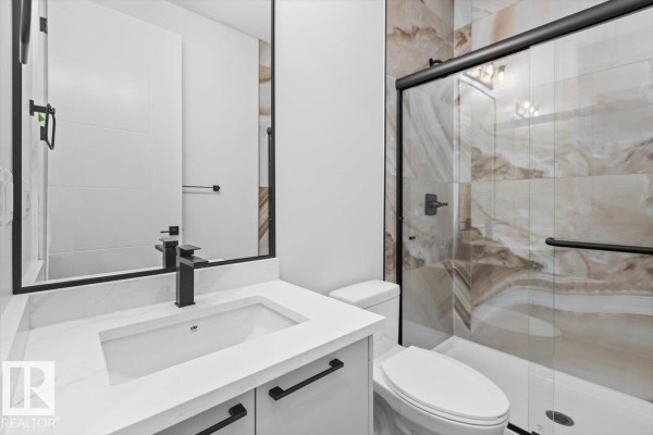 Bathroom with a white vanity, marble tile shower with a glass door, and a modern toilet. - 21 Sorel Av, Beaumont
