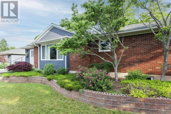 Front view of a single-story house with brick and blue siding, concrete walkway, and steps. - 21 Spring Garden Road, Middleton