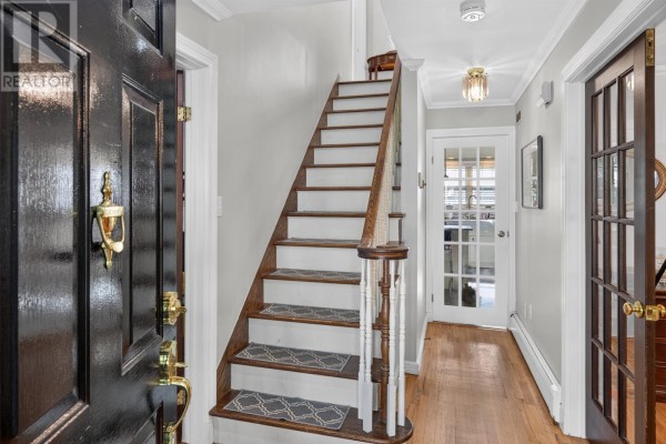 Entrance hallway with dark wood front door, wooden staircase, and French doors. - 21 Symonds Place, St  John’s