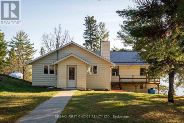 Front view of the building featuring a porch, chimney, and pathway leading to the entrance. - 21 Tinker's Road, Sioux Narrows Nestor Falls