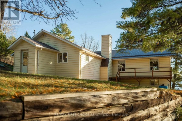 Side angle of the building showcasing the deck and landscaped yard with a retaining wall. - 21 Tinker's Road, Sioux Narrows Nestor Falls