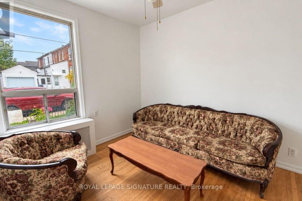 Living room with floral patterned sofa and armchair, wooden coffee table, and large window. - 21 Via Italia, Toronto