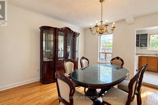 Formal dining room with oval glass-top table, chairs, and a large wooden china cabinet. - 21 Via Italia, Toronto