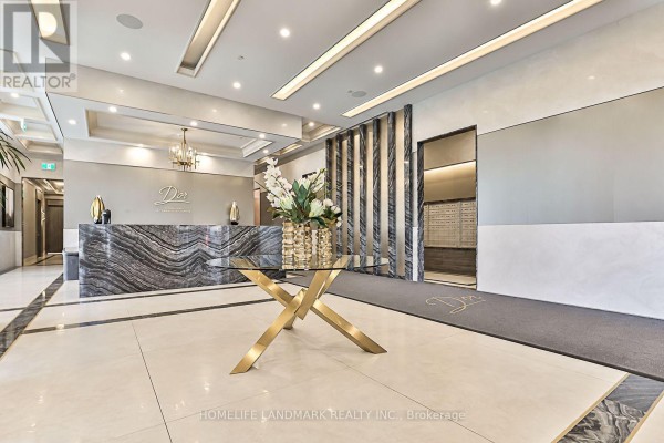 Building lobby with a marble reception desk, golden accents, and tiled floors. - 210 - 10 Gatineau Drive, Vaughan
