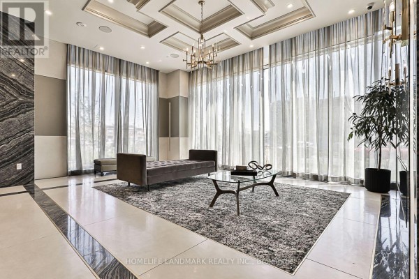 Building lobby seating area with a tufted bench, glass coffee table, and floor-to-ceiling curtains. - 210 - 10 Gatineau Drive, Vaughan