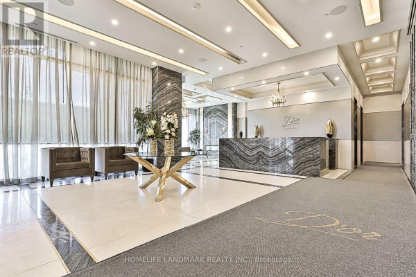 Building lobby with marble reception desk, plush seating, and ornate chandelier lighting. - 210 - 10 Gatineau Drive, Vaughan