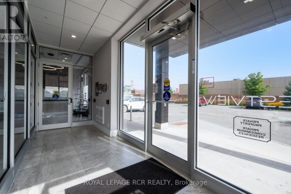 Glass entrance doors to the apartment building lobby with automatic openers and exterior view. - 210 - 105 Spencer Avenue, Orangeville
