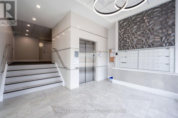 Apartment building lobby with a stainless steel elevator, marble tile floor, and mailboxes. - 210 - 105 Spencer Avenue, Orangeville