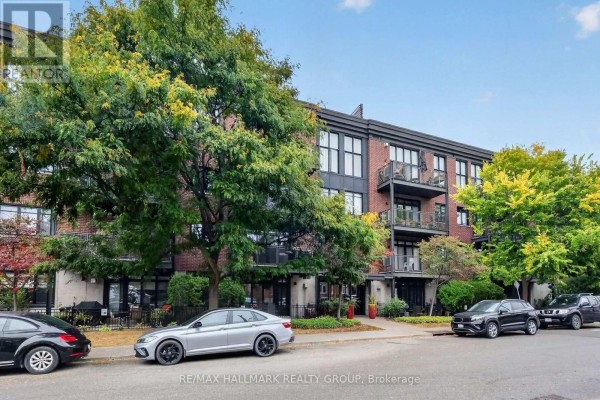 Front view of a modern brick apartment building with balconies and mature trees. - 210 - 457 Mcleod Street, Ottawa