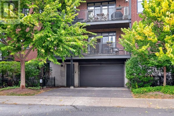 Close-up view of the apartment building's ground-level garage entrance with modern architecture and landscaping. - 210 - 457 Mcleod Street, Ottawa