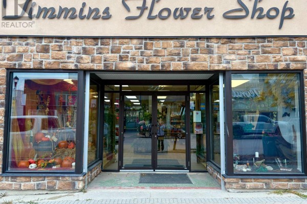 Entrance to Timmins Flower Shop with double glass doors, flanked by large display windows showing autumn decor. - 210-212 Third Avenue, Timmins