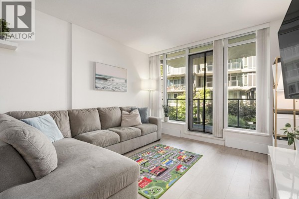 Living room with large windows showing a courtyard view and trees. - 210 3168 Riverwalk Avenue, Vancouver