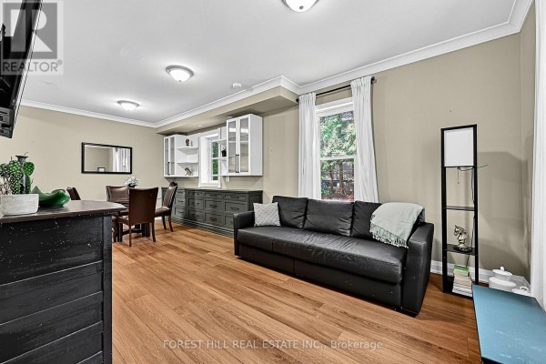 Living and dining area with a black sofa, wooden floors, dining set, and built-in white and grey cabinets. - 210 Centennial Drive, Midland