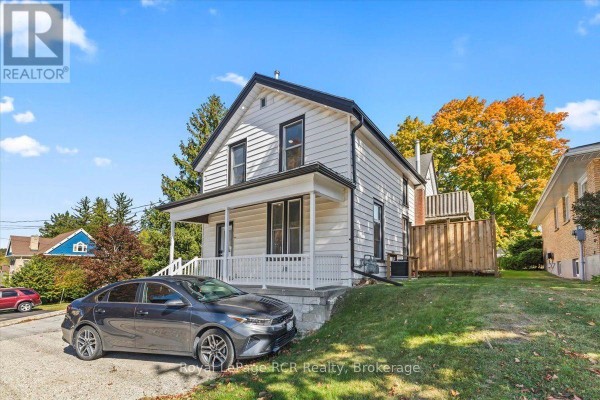 Side view of the white vinyl-sided house with a grey car in the driveway. - 210 Colborne Street S, Brockton