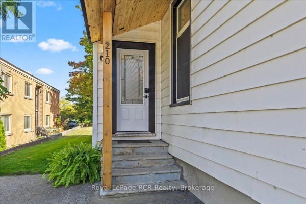 Close-up of the front door with house number 210 and concrete steps. - 210 Colborne Street S, Brockton