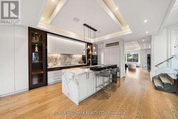 Modern kitchen with marble island, bar stools, pendant lights, and glass railing staircase - 210 Horsham Avenue Toronto