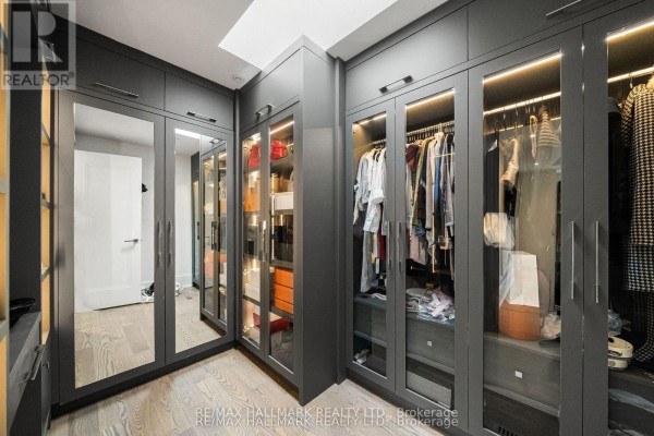Walk-in closet with glass-front cabinets, mirrored doors, and built-in shelving - 210 Horsham Avenue Toronto