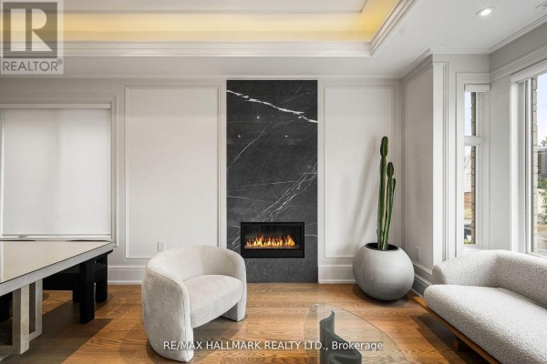 Close-up of a living room fireplace with black marble, modern chairs, and tall planter. - 210 Horsham Avenue, Toronto
