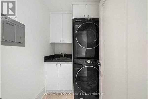 Stacked Samsung washer and dryer with sink and white cabinets - 210 Horsham Avenue Toronto