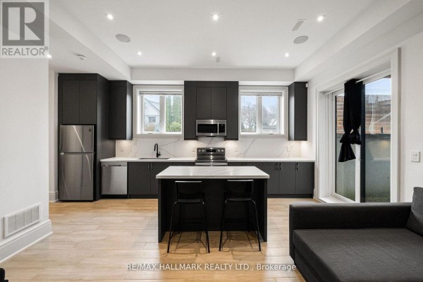 Modern kitchen with dark cabinets, island, and stainless steel appliances - 210 Horsham Avenue Toronto