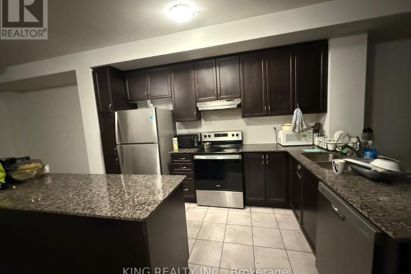 Kitchen with dark brown cabinets, granite countertops, stainless steel appliances, and tile flooring. - 210 Keppel Circle, Brampton