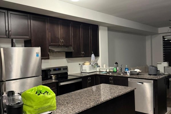 Kitchen with dark brown cabinets, granite countertops, stainless steel appliances, and island. - 210 Keppel Circle, Brampton