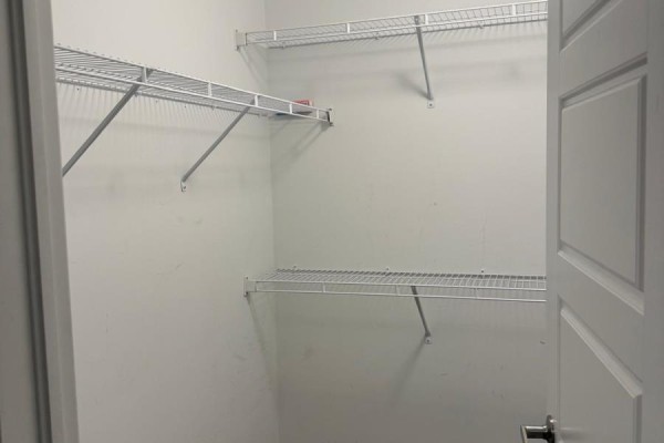 Empty walk-in closet with white wire shelving on three walls. - 210 Keppel Circle, Brampton