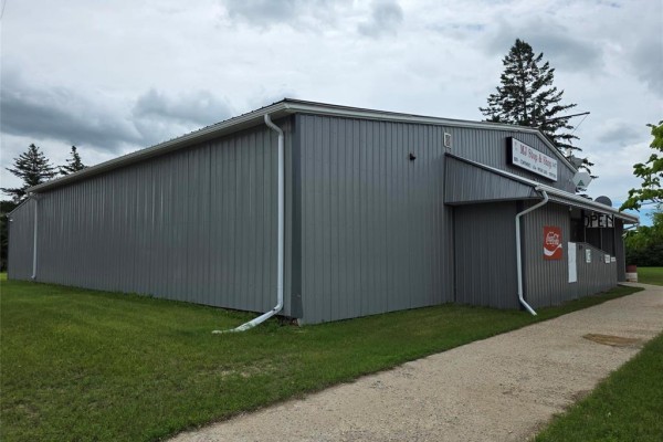 Exterior of the commercial building showing grey siding and walkway. - 201 Main Street, Langruth
