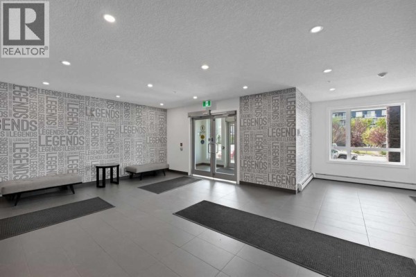 Building lobby with grey tiled floors, benches, and large glass doors. - 2101, 76 Cornerstone Passage Ne, Calgary