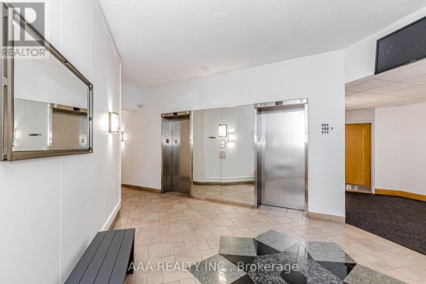 Building lobby with two elevators, mirrored walls, sconce lighting, and a bench. - 2101 - 5 Concorde Place, Toronto
