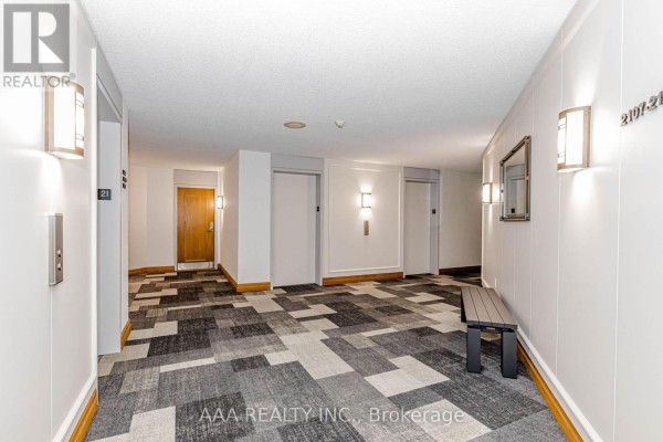 A building hallway with elevators, carpeted floor, sconce lighting, and a bench. - 2101 - 5 Concorde Place, Toronto