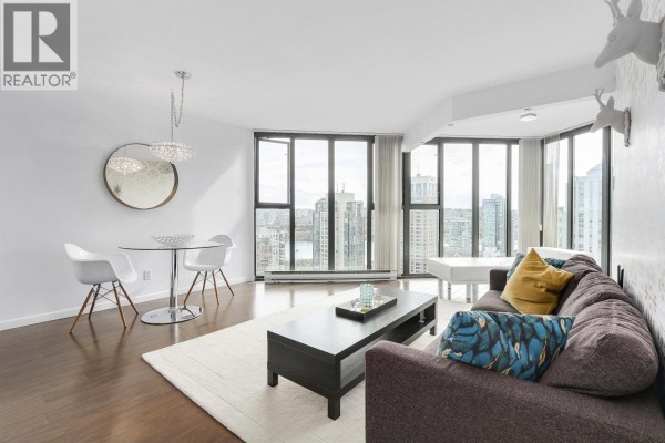 Living and dining area with dark wood floors, a sectional sofa, and city views. - 2102 1155 Homer Street, Vancouver