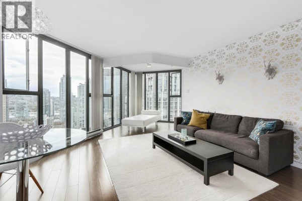 Living area with a sectional sofa, decorative wall, and floor-to-ceiling windows. - 2102 1155 Homer Street, Vancouver