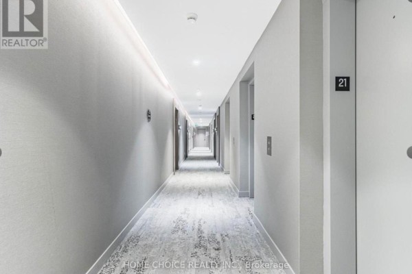 Long hotel-style interior hallway with elevators and numbered doors on both sides. - 2103 - 161 Roehampton Avenue, Toronto
