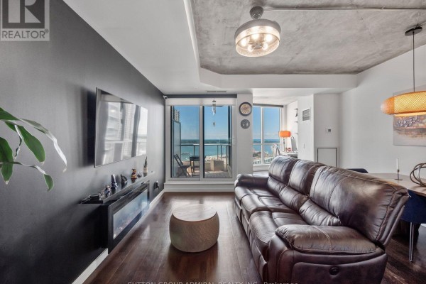 Living room with brown leather sofa, granite island, and city view through balcony doors. - 2103 - 218 Queens Quay Boulevard W, Toronto